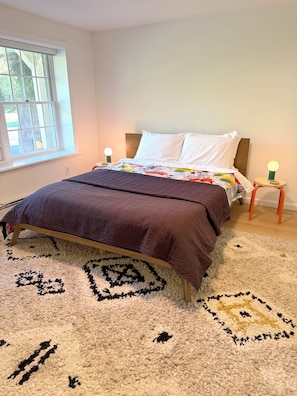 A bedroom with a bed, a window, a nightstand, and a rug. - Tranquil, stylish apartment in the heart of the Hudson Valley (Newburgh)