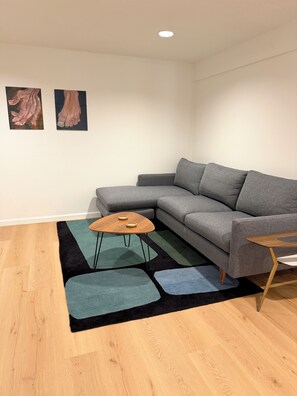 A living room with a grey sofa, a wooden coffee table, and a patterned rug. - Tranquil, stylish apartment in the heart of the Hudson Valley (Newburgh)