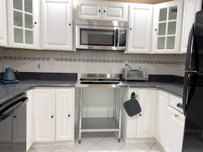 A kitchen with white cabinets, a microwave, a toaster, and a black refrigerator. - Tranquil, stylish apartment in the heart of the Hudson Valley (Newburgh)