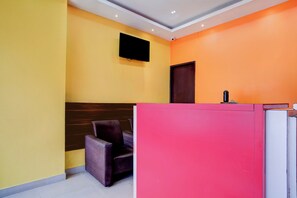 A reception area with a reception desk, a chair, and a flat-screen TV mounted on the wall. - Hotel O Sankaradeva Kalakshetra (Guwahati)