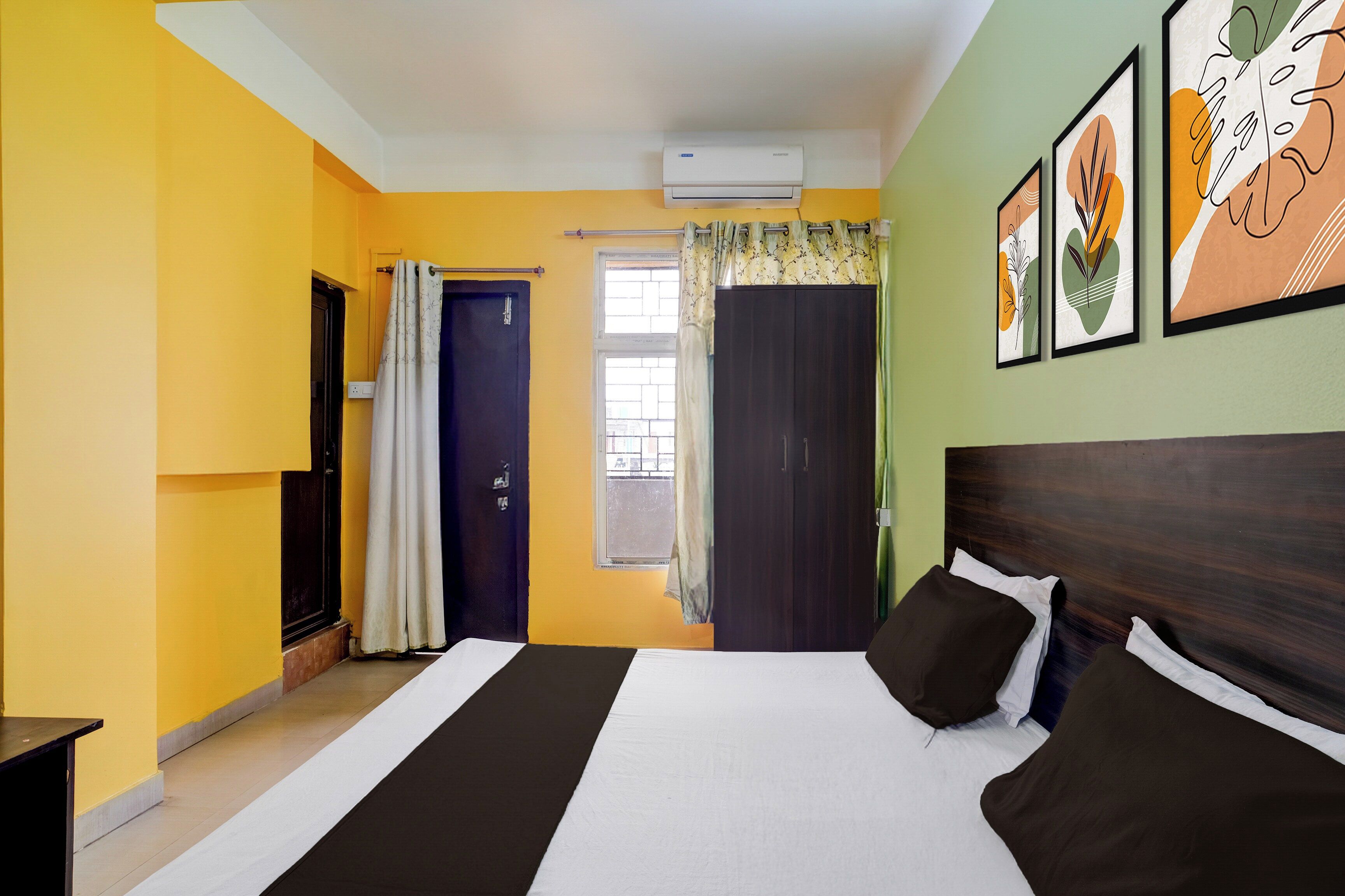 Een hotelkamer met een bed, raam, airconditioning en een deur.