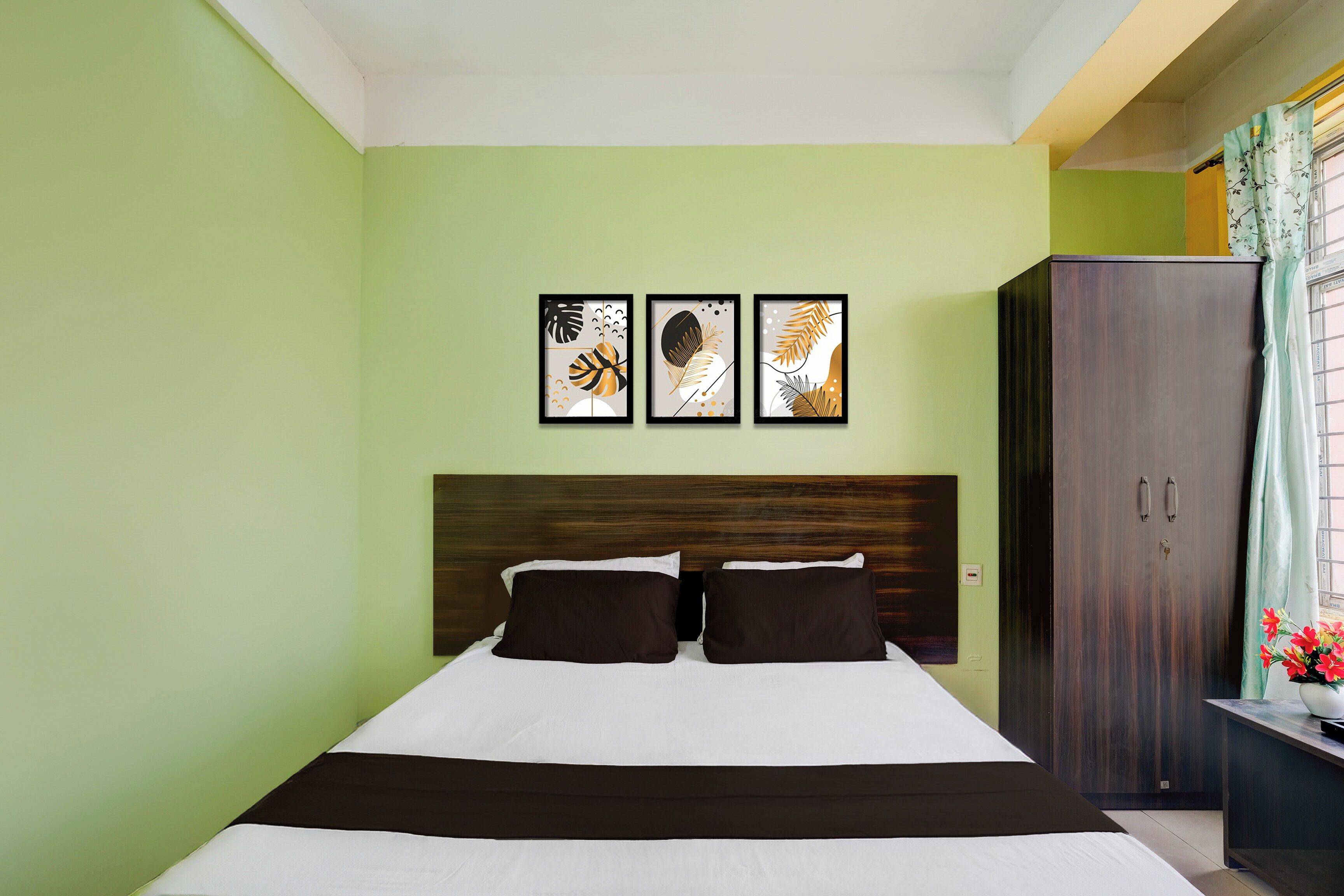 A bedroom with a bed, a wardrobe, and three framed artworks on the wall.