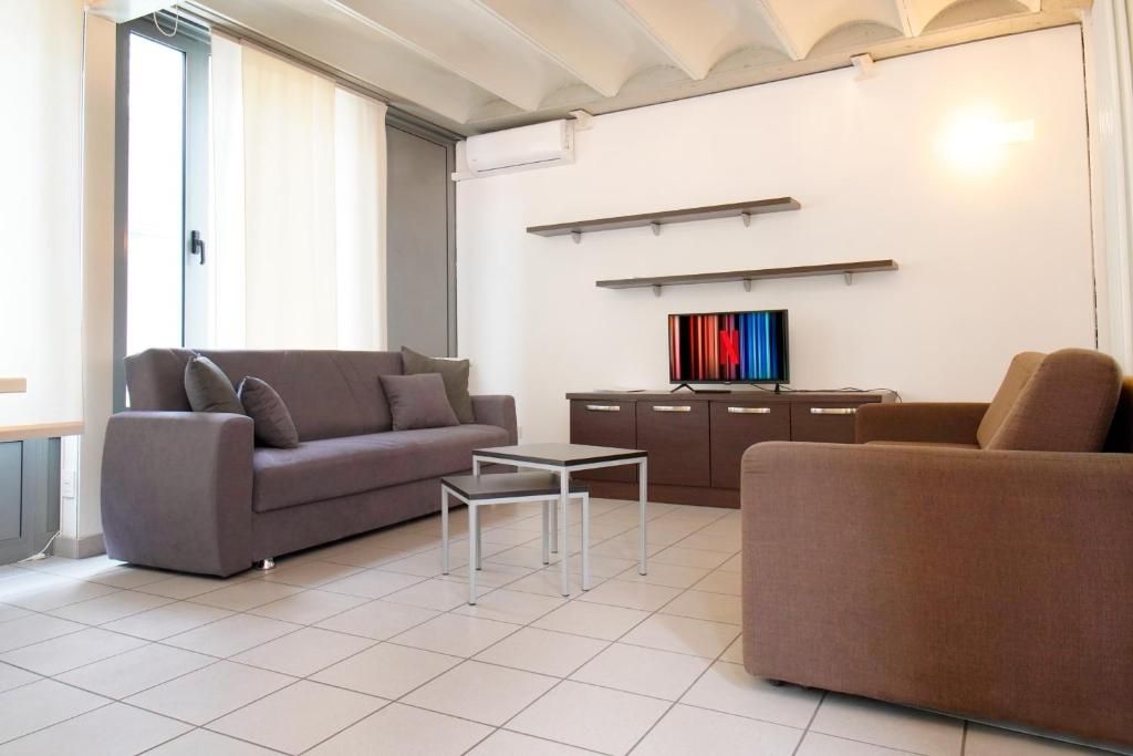 En moderne stue med sofa, sofabord og et fladskærms-tv på et skab.