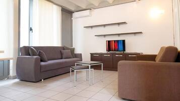 En moderne stue med sofa, sofabord og et fladskærms-tv på et skab.