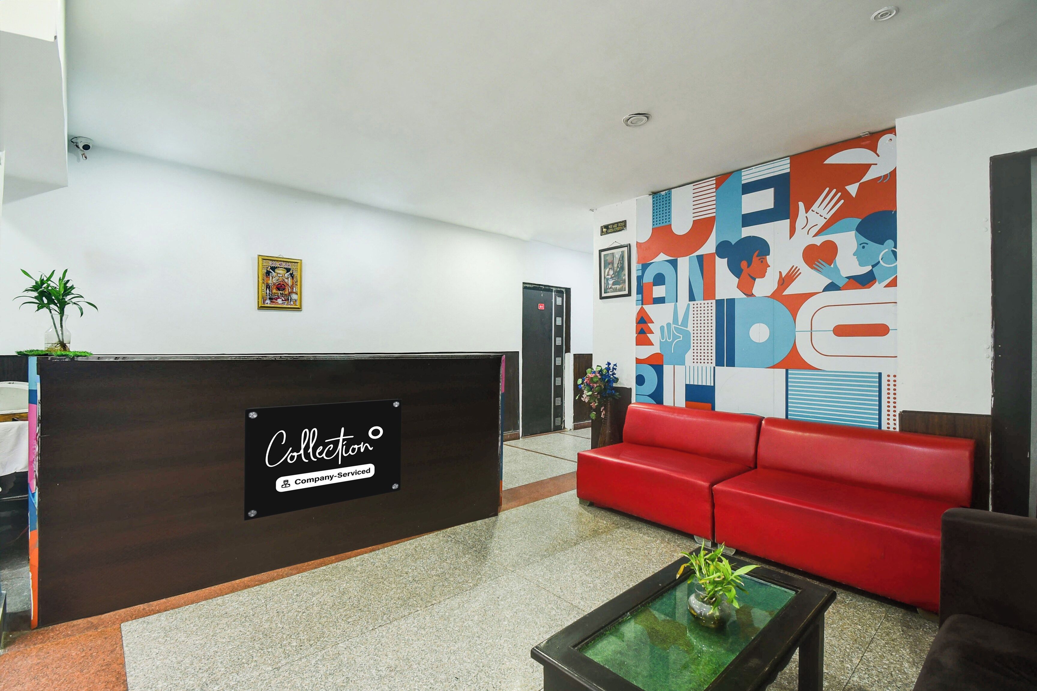 A reception area with a dark reception desk, a red sofa, and a glass coffee table.