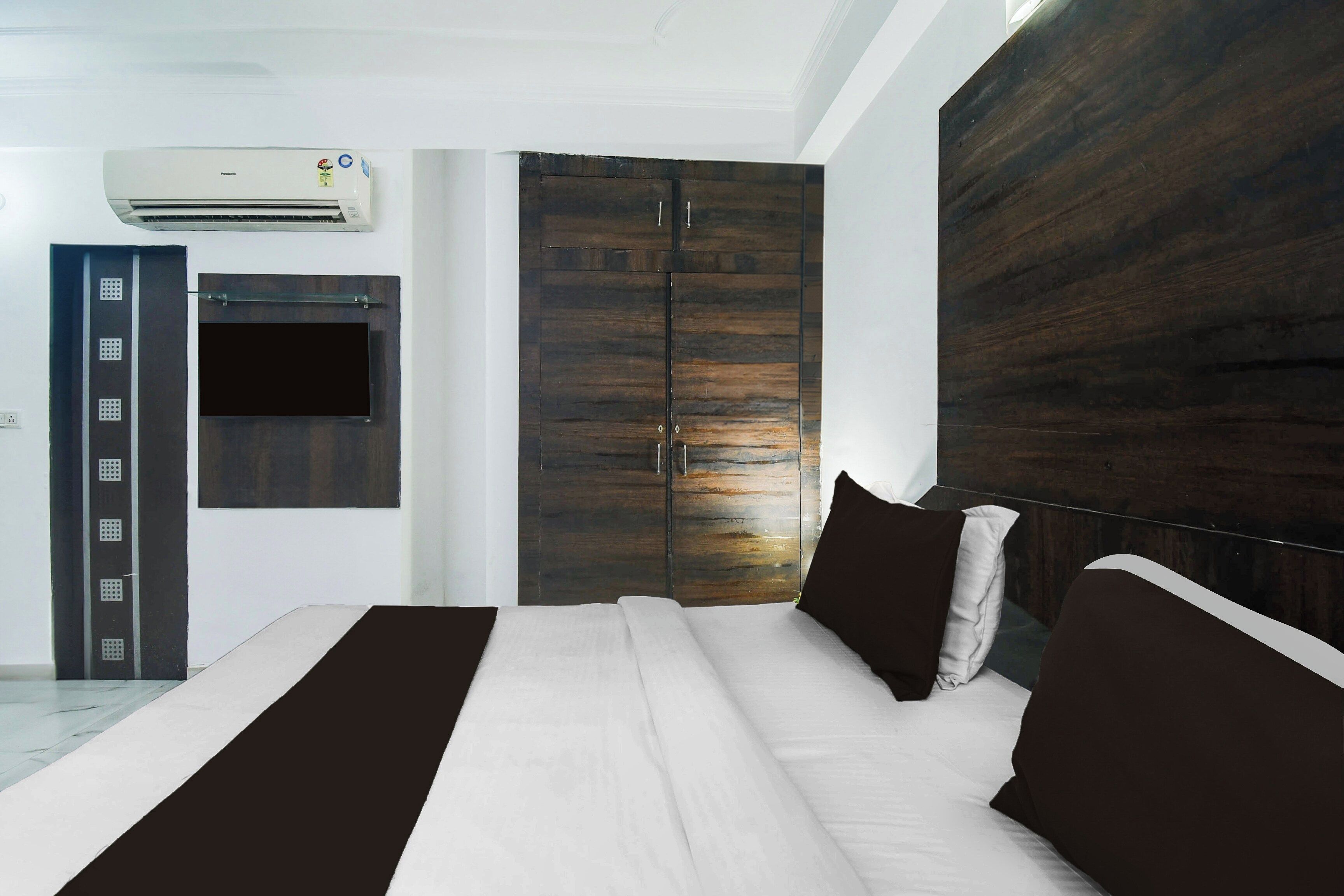 A bedroom with a bed, a wardrobe, a door, and an air conditioning unit.