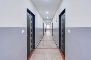 Un passadís llarg i estret amb portes a ambdós costats, que condueix a una habitació lluminosa al final.
