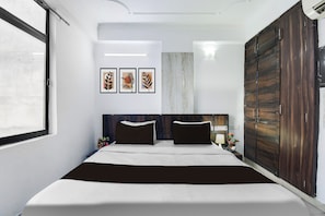 Ein Schlafzimmer mit einem Bett, einem Kleiderschrank, einem Nachttisch und Wandbildern.