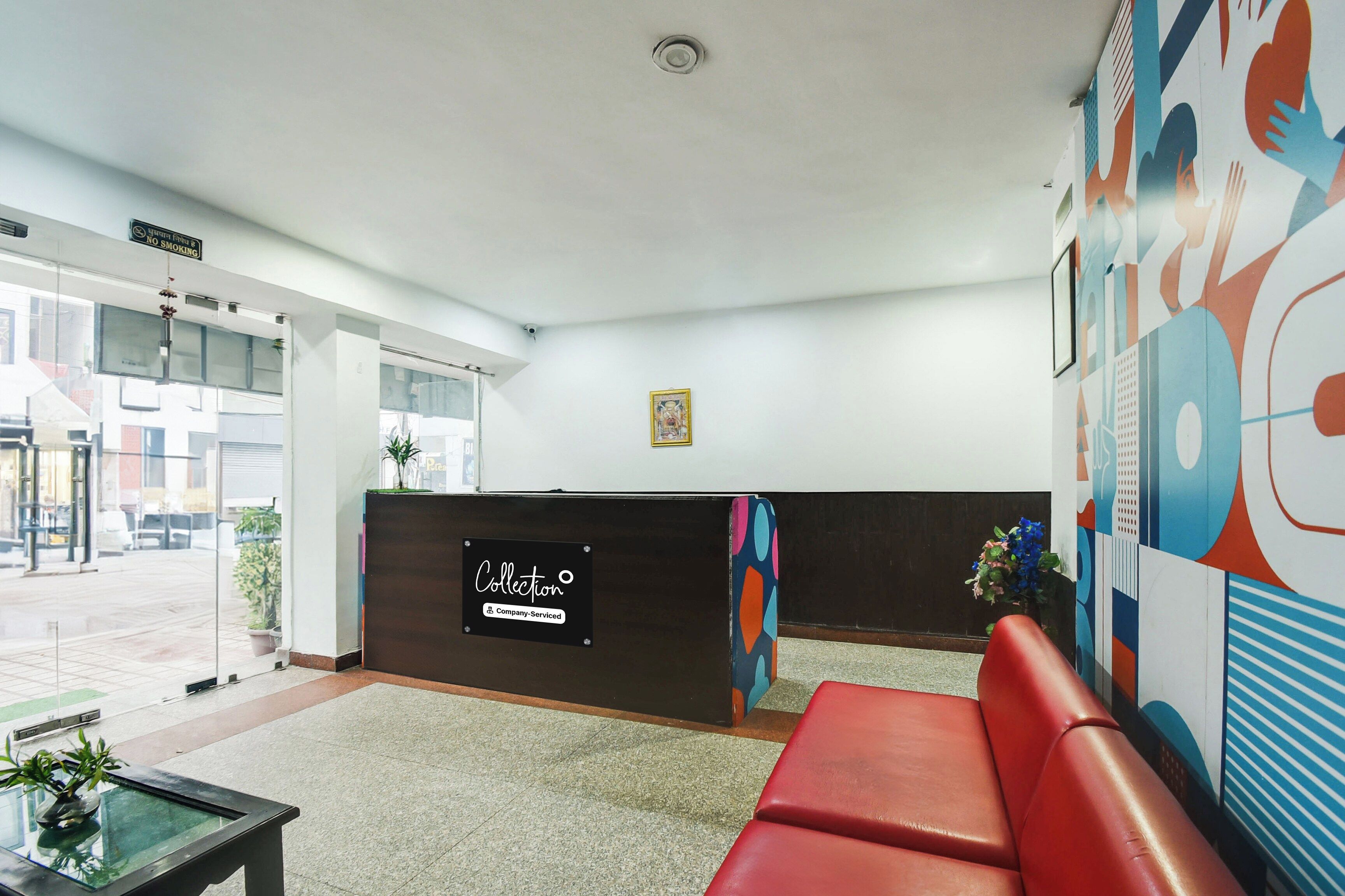 A reception area with a modern design, including a reception desk, a red sofa, and a wall with abstract art.