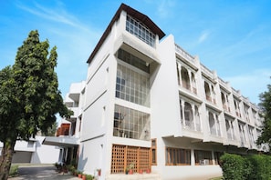 A modern building with multiple windows and balconies, surrounded by greenery. - Townhouse Pichola (Udaipur)