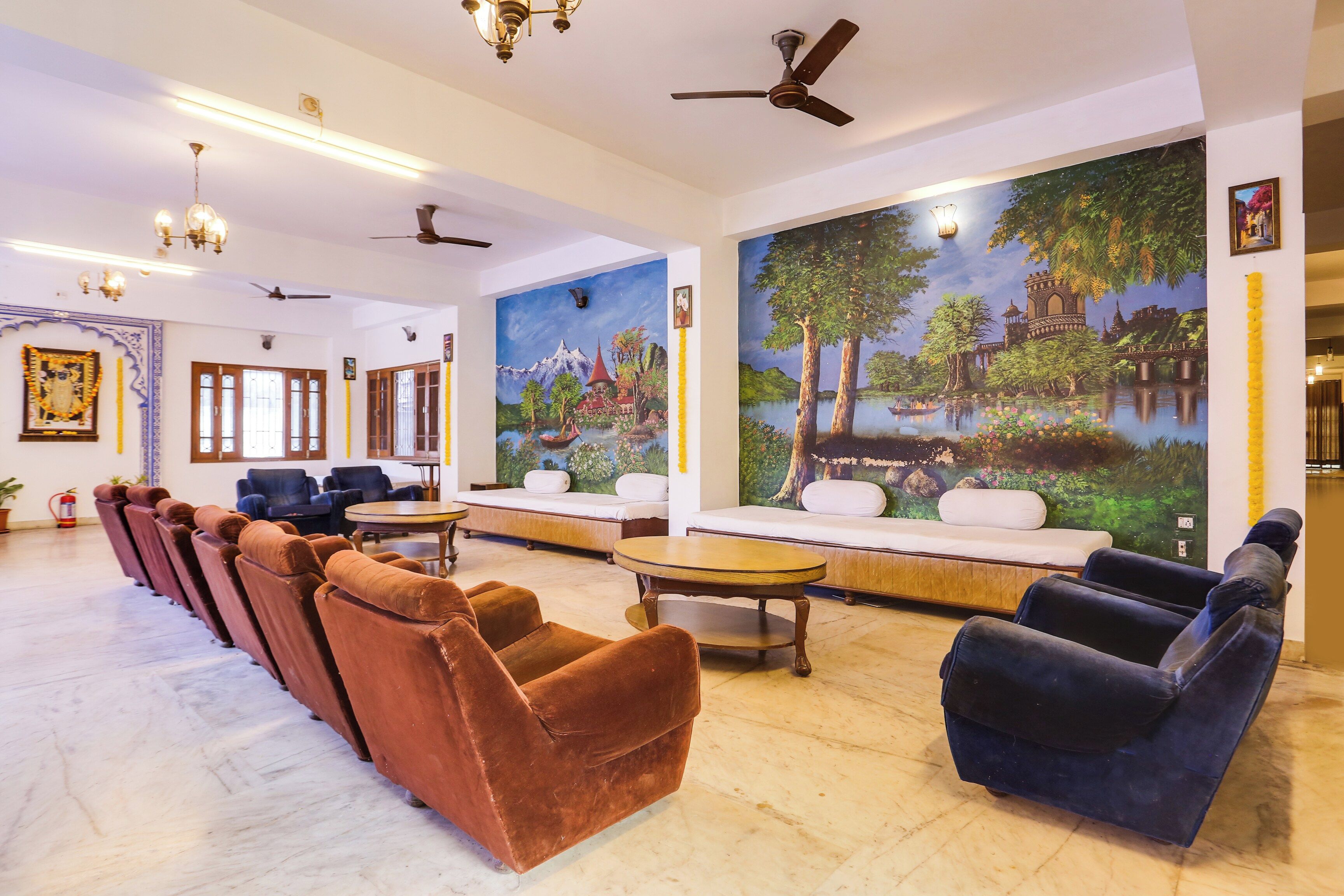A hotel lobby with a row of sofas, a dining table, and a large mural on the wall.