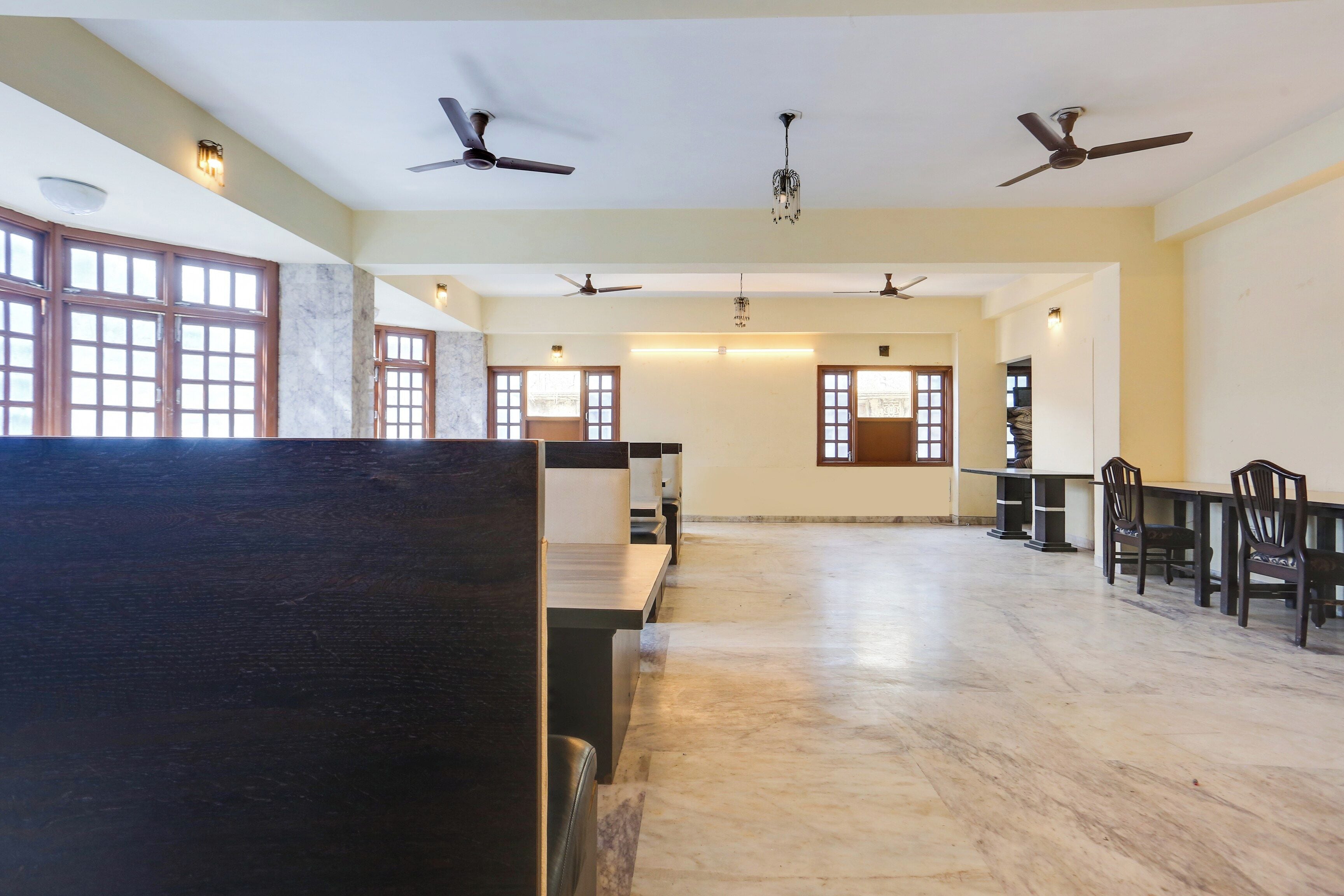 A spacious room with multiple ceiling fans, a long table with chairs, and a large window with a view.