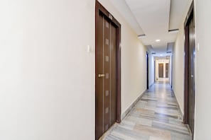 A hotel hallway with a marble floor, wooden doors, and a ceiling with recessed lighting. - Hotel O Sarat Bose Road (Kolkata)
