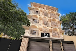 A multi-story hotel with balconies, a sign indicating it is company-serviced, and a closed garage door. - Hotel O Sarat Bose Road (Kolkata)