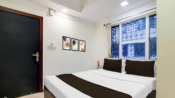 Habitación de hotel con cama, puerta, ventana con vistas y una obra de arte colgada en la pared.