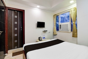 A hotel room with a bed, a television mounted on the wall, a window with curtains, and a door with a security lock. - Hotel O Sarat Bose Road (Kolkata)