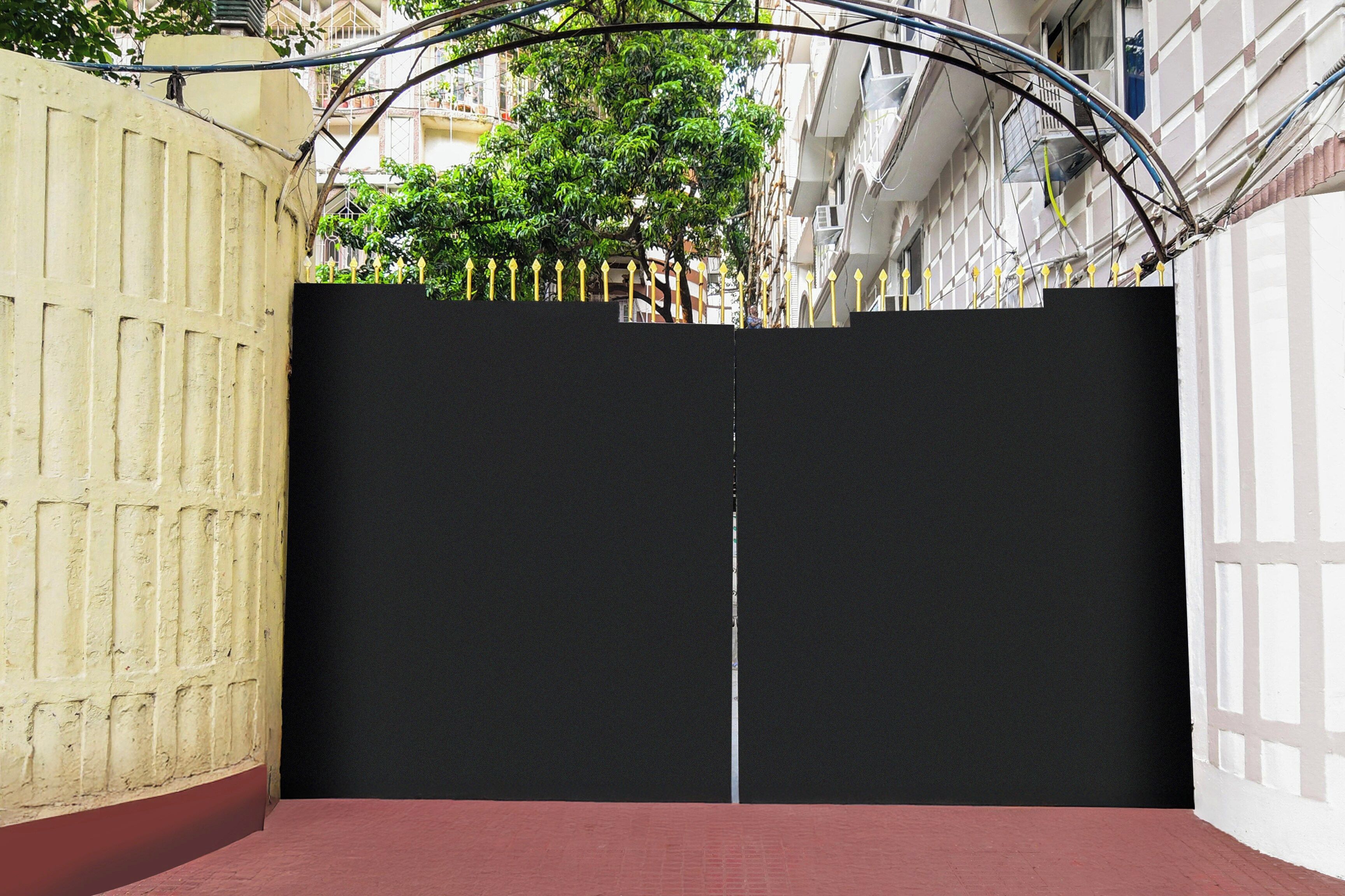 A closed black gate with a metal fence on a red brick pavement, surrounded by buildings.