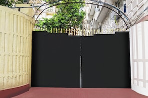 A closed black gate with a metal fence on a red brick pavement, surrounded by buildings. - Hotel O Sarat Bose Road (Kolkata)