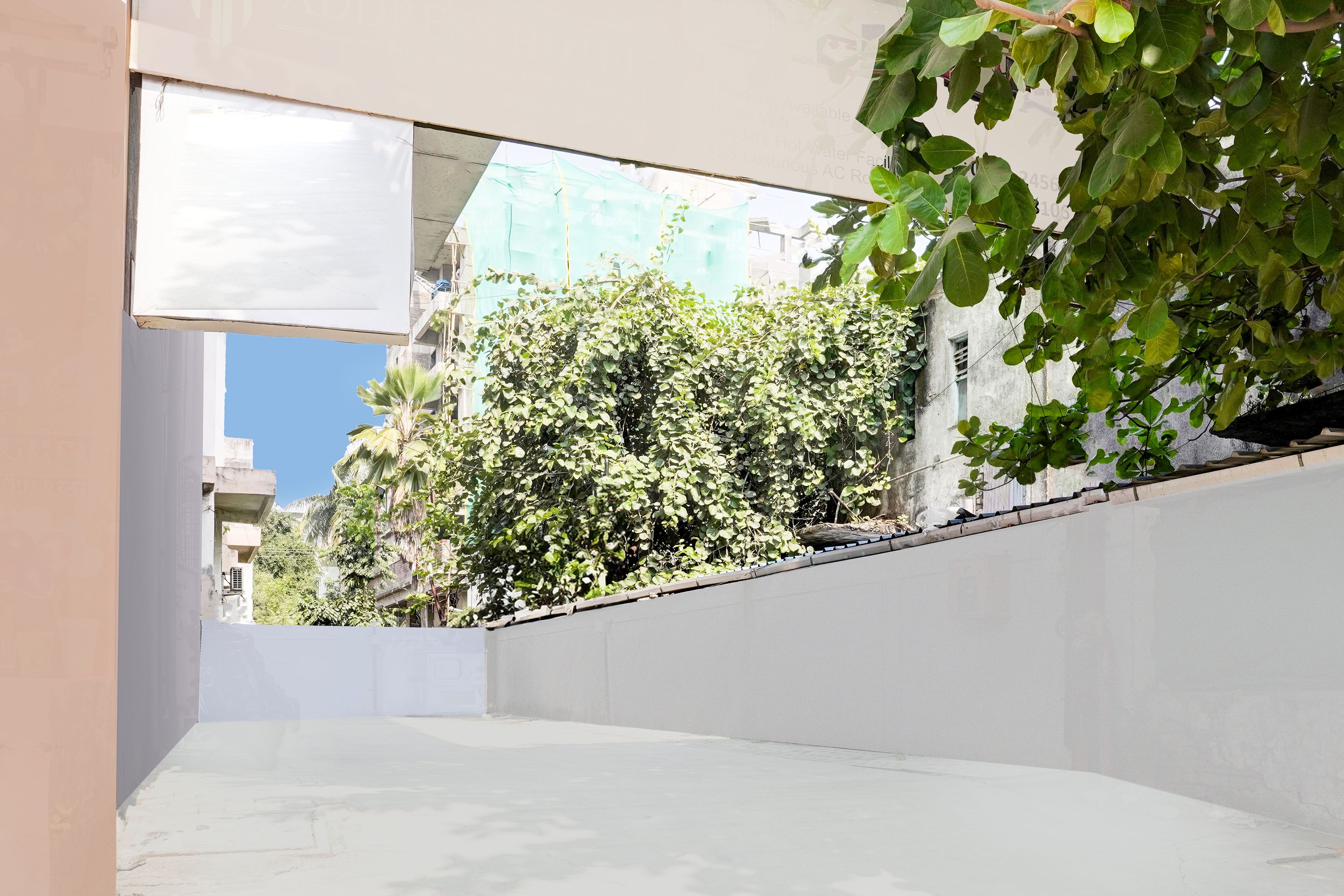 A narrow outdoor corridor with a concrete wall on one side and a building with a balcony on the other.