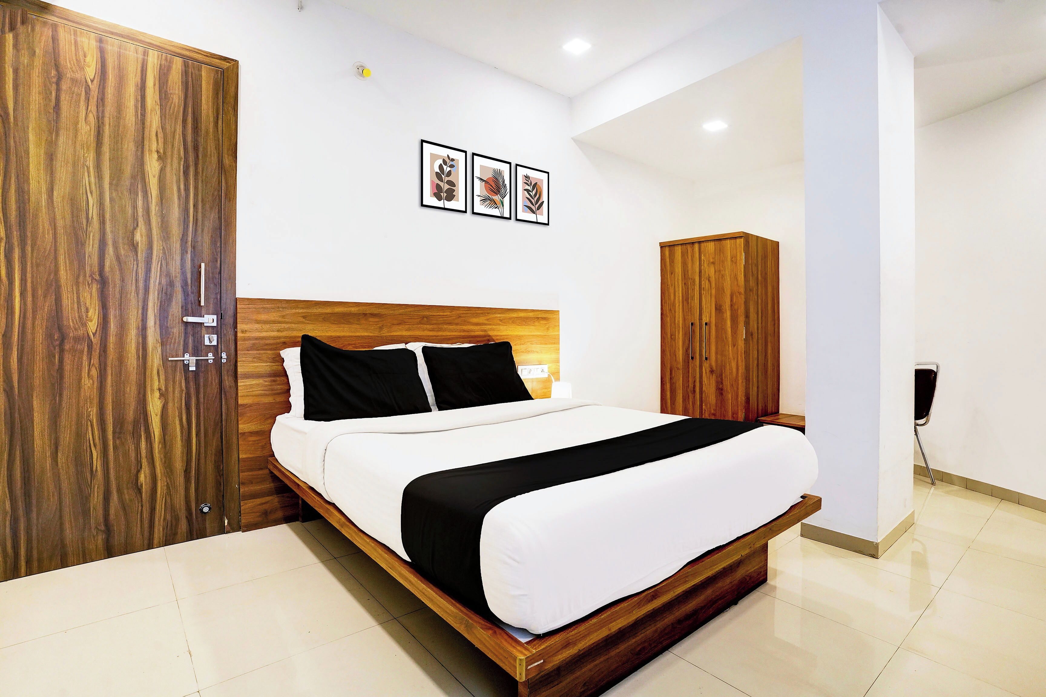 A hotel room with a wooden bed, a wardrobe, and a cabinet.