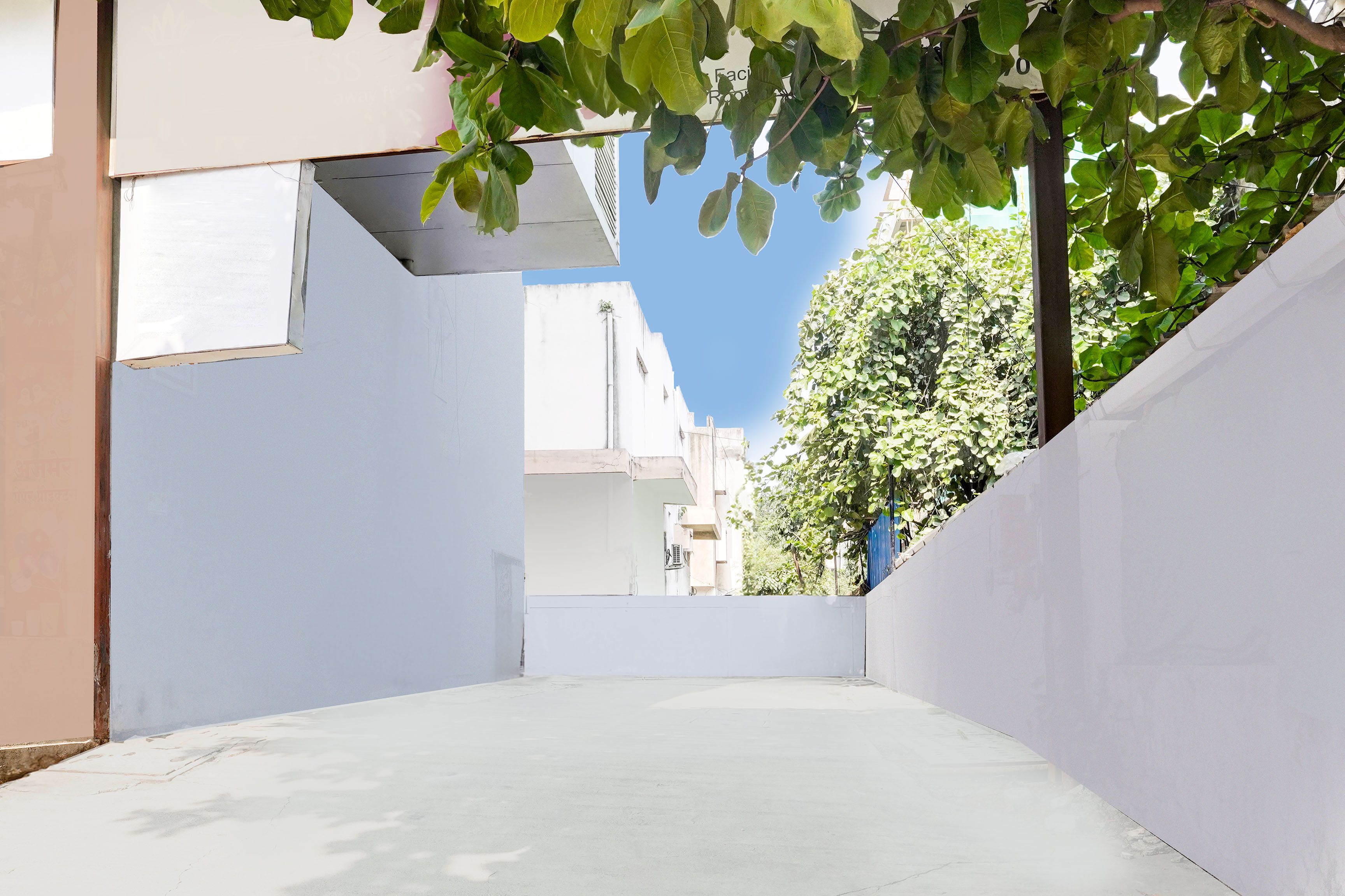 A narrow alleyway with white walls and a clear blue sky above.