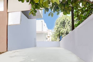 A narrow alleyway with white walls and a clear blue sky above.