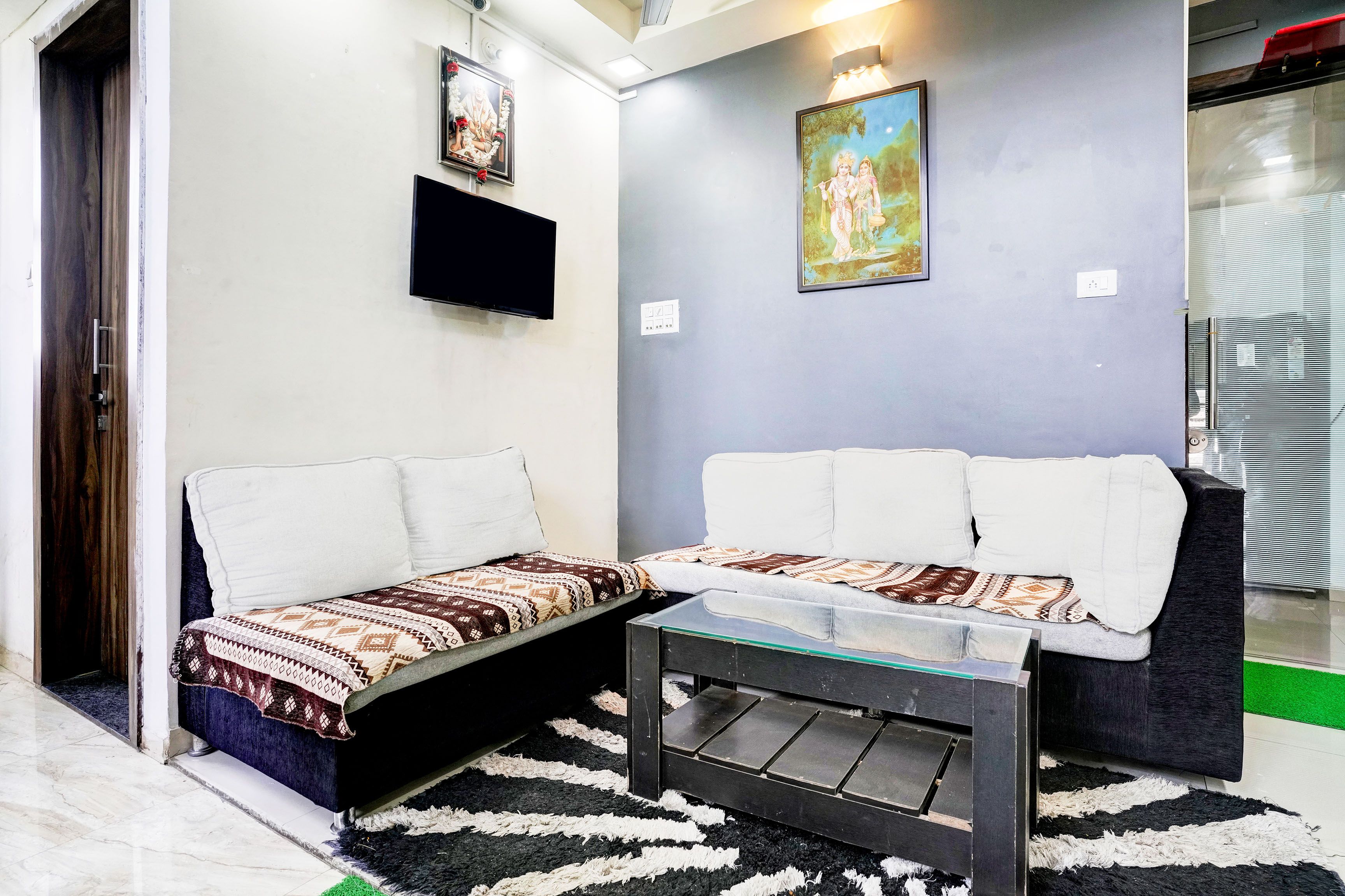 A living room with a sofa, a coffee table, and a flat-screen TV mounted on the wall.