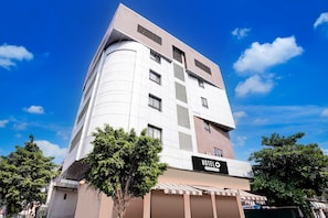 A modern hotel with a curved facade, multiple windows, and a sign indicating it is a company-serviced hotel.