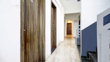 A hallway with wooden doors, a tiled floor, and a staircase with a blue accent.