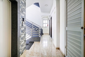 A hallway with a marble floor, a staircase with a metal railing, and a door with a security keypad. - Hotel O Nashik Road (Nashik)