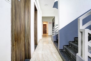 A hallway with a wooden door, a staircase, and a sign indicating CCTV surveillance.