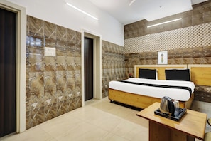 Habitación de hotel con una cama, una mesita de noche de madera, un marco de fotos y un diseño estampado en la pared.