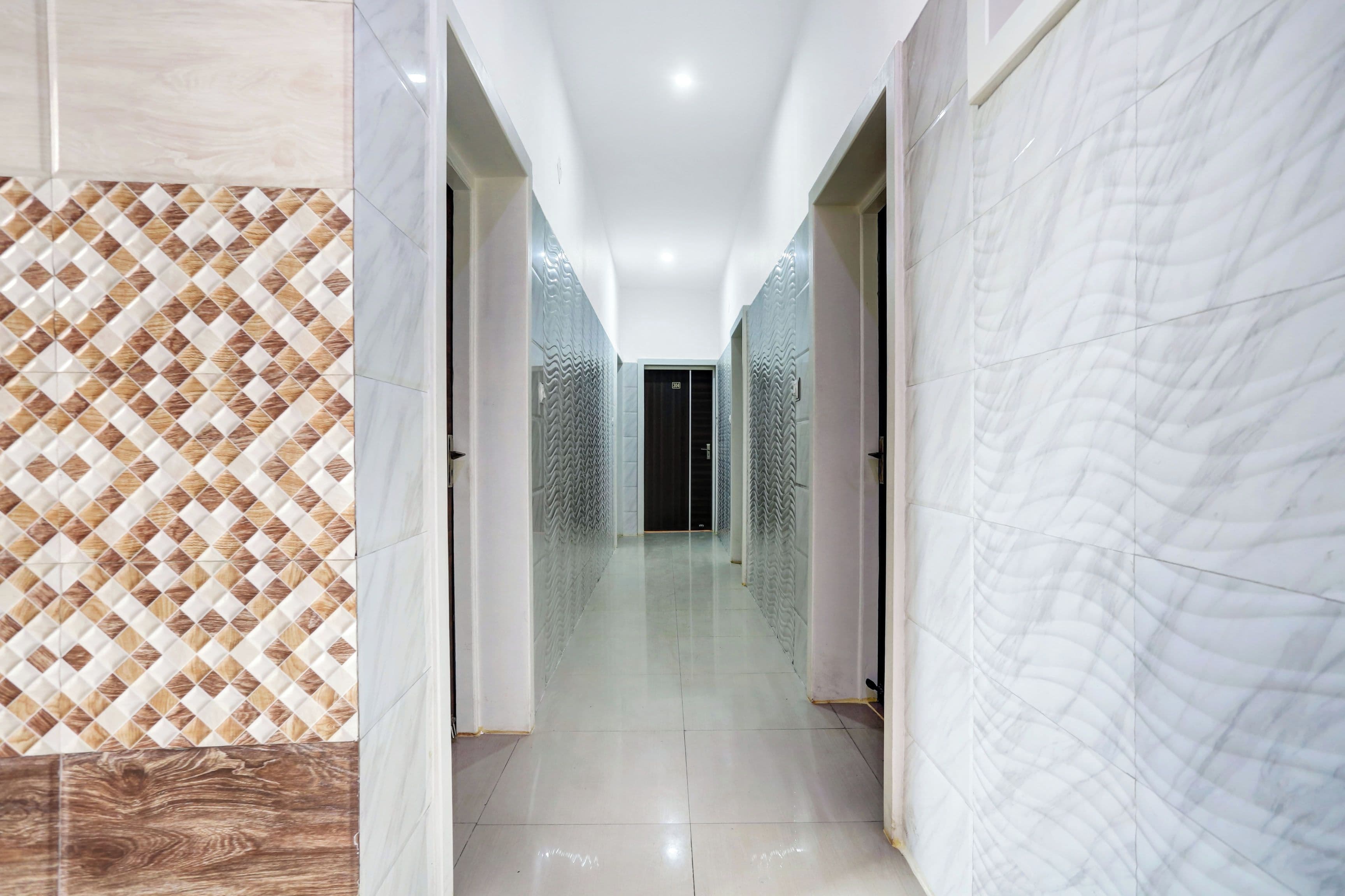 A hallway with patterned walls and a glossy floor, leading to a dark room.