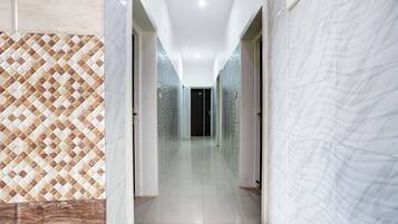 A hallway with patterned walls and a glossy floor, leading to a dark room.