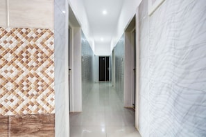 Un pasillo con paredes decoradas y suelo brillante, que conduce a una habitación oscura.