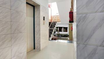 A hallway with marble flooring, a door, and a staircase leading to a building with a patterned facade.