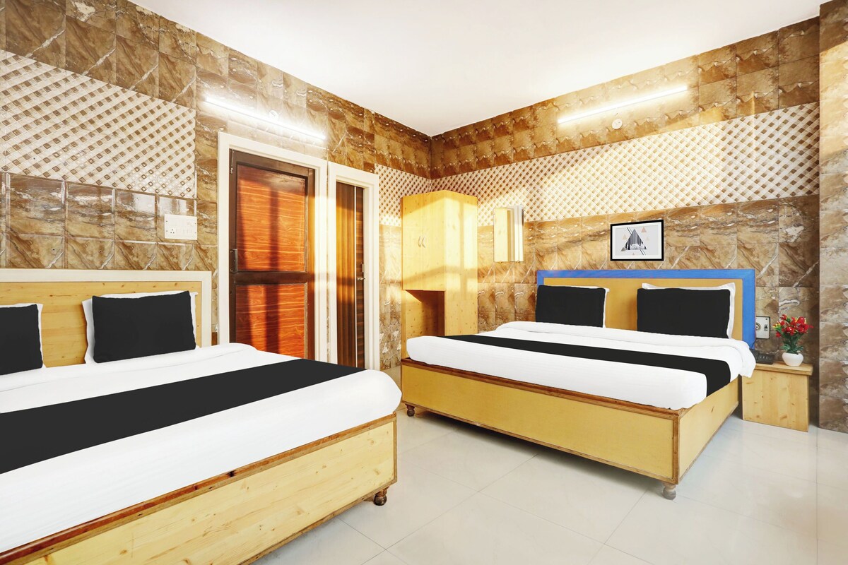 A hotel room with two beds, a wooden headboard, a mirror, a wall-mounted picture, and a tiled floor.