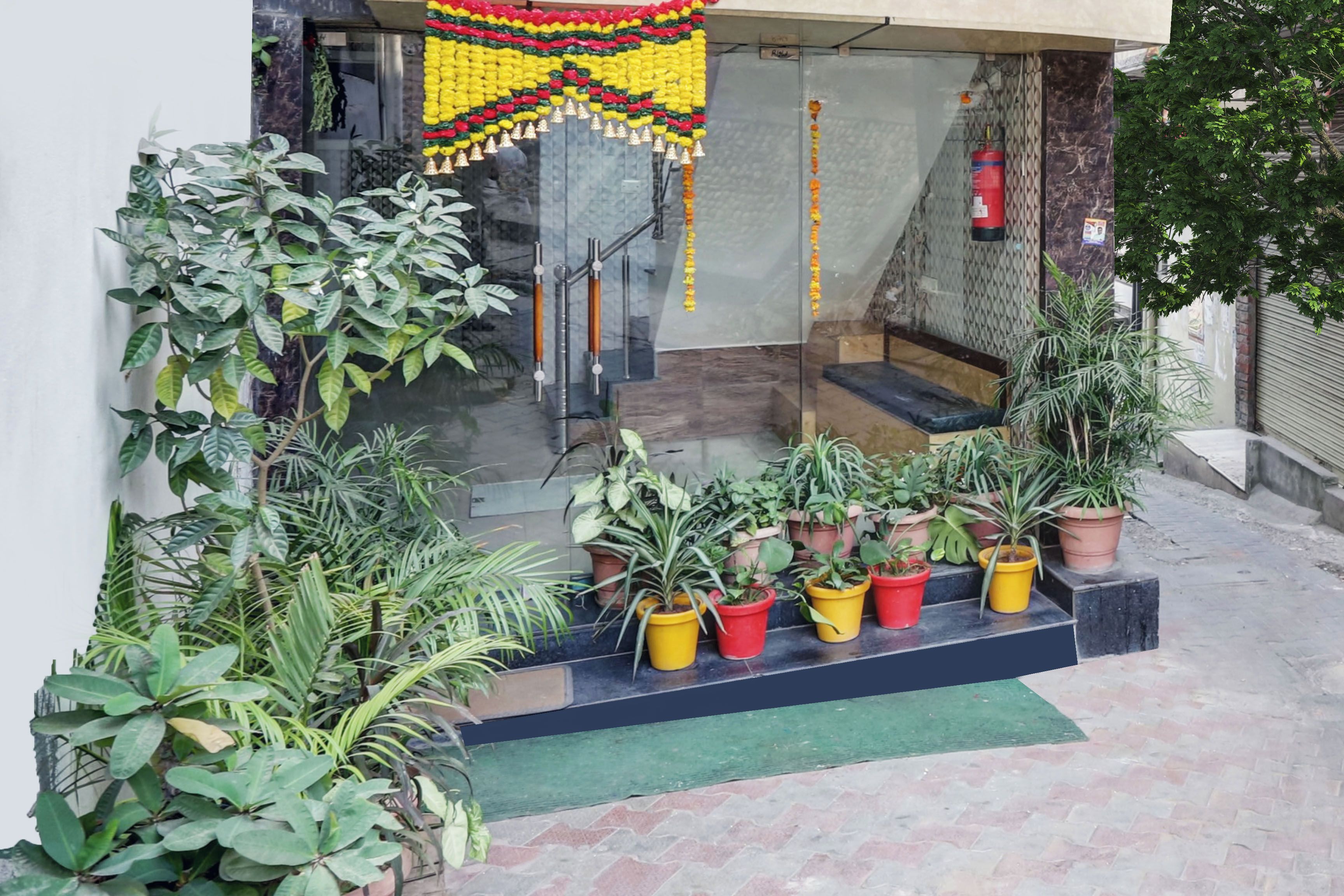 A building entrance with a staircase, potted plants, and a decorative garland.