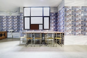 Comedor con un ventanal grande, salpicadero de azulejos y una mesa redonda con sillas.