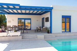 Ein überdachter Außenbereich mit Pool, Esstisch und Stühlen.
