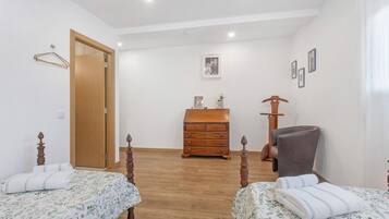 Un dormitorio con dos camas, un aparador de madera, una silla y un armario de madera.