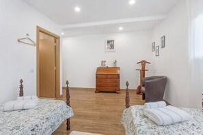 Un dormitorio con dos camas, un aparador de madera, una silla y un armario de madera.