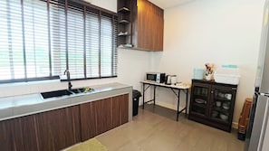 A modern kitchen with a built-in sink, a microwave, a kettle, and a cabinet with dishes. - Ellieriviera Pool Villa ชะอำ-หัวหิน
Private Retreat 
บ้านพักส่วนตัว (Tambon Huai Sai Nuea)