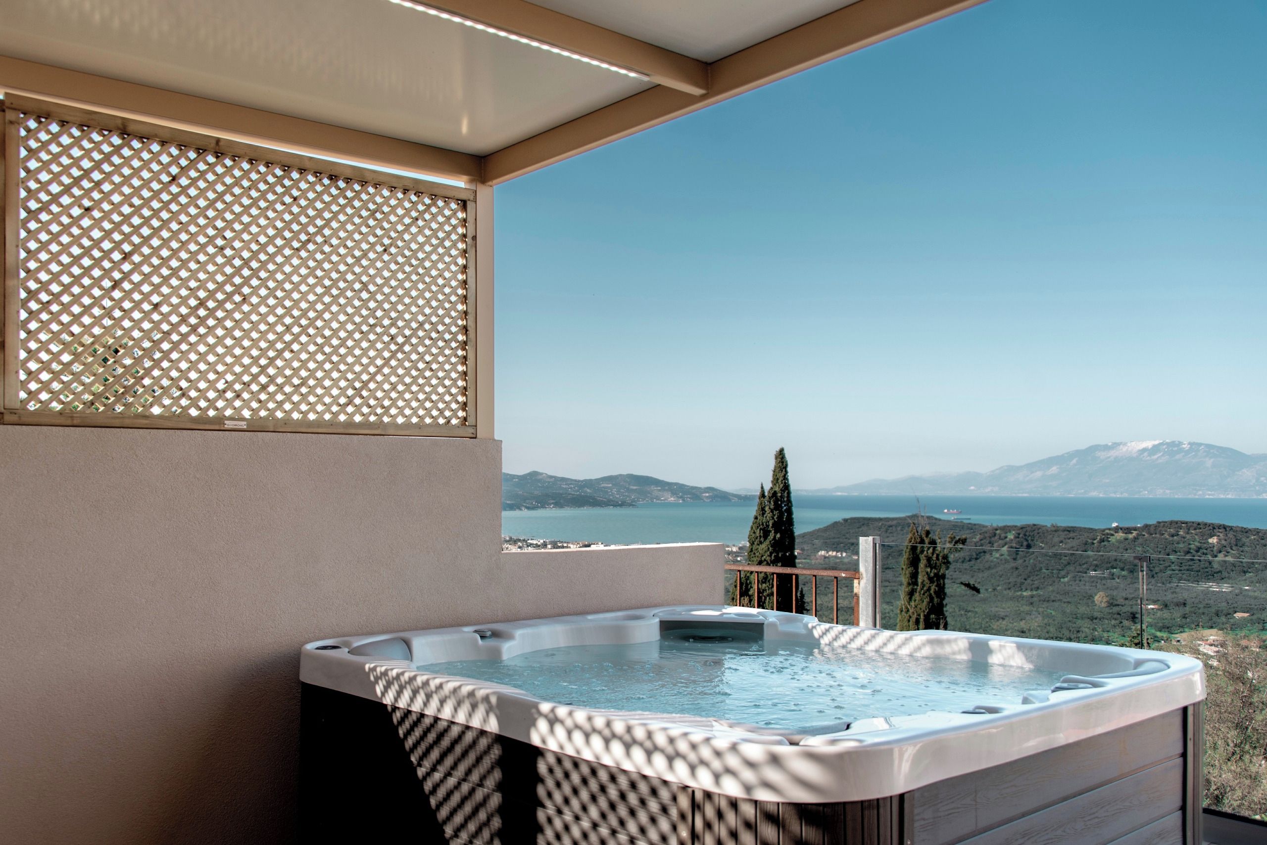 A hot tub on a balcony with a view of a lake and mountains.