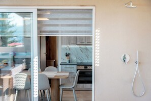 A modern kitchen with a marble countertop, wooden cabinets, and a built-in oven. - Magic View Apartment (Zakynthos)