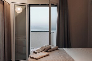 A hotel room with a bed, a view of the beach, and a sliding door to the outside. - Magic View Apartment (Zakynthos)