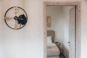 Un dormitorio con una cama, una mesita de noche y un reloj en la pared.