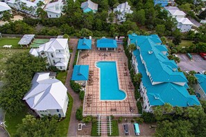 Ein Wohnkomplex mit einem zentralen Schwimmbecken, mehreren Gebäuden mit blauen Dächern und einem gepflegten Rasen.
