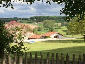 A rural landscape with a white building with a red roof, surrounded by green fields and trees. - Holiday Home 'Les Deux Indeaux' with Wi-Fi (Lusignac)