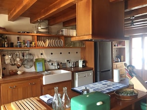 Une cuisine avec des meubles de rangement en bois, un évier, un réfrigérateur et divers ustensiles de cuisine.